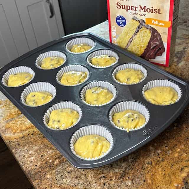 Cupcake tray with cupcake paper liners and batter inside.