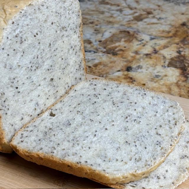 Slices of bread machine chia seed bread on a wooden cutting board.