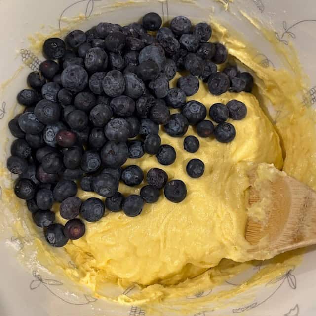 Blueberries being added to cake mix muffins batter.