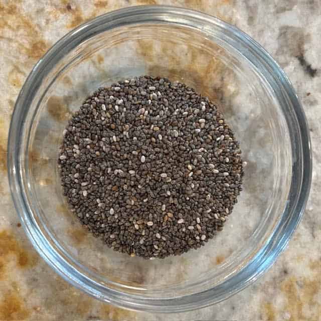Chia seeds in a small glass bowl on a kitchen counter.