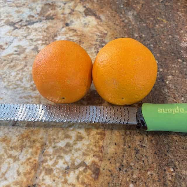 Two oranges and a zesting tool used to make my cranberry orange muffins recipe.