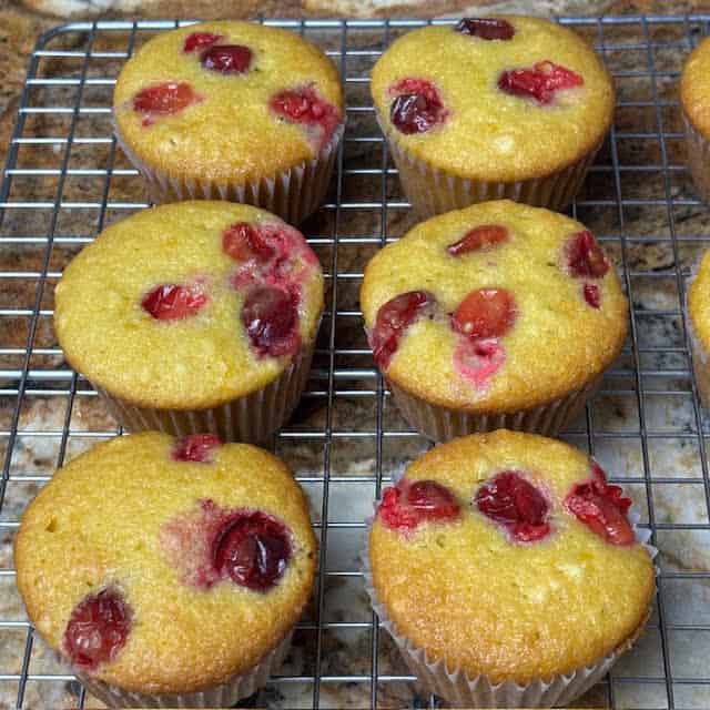 Six cranberry orange muffins on a wire cooling rack.