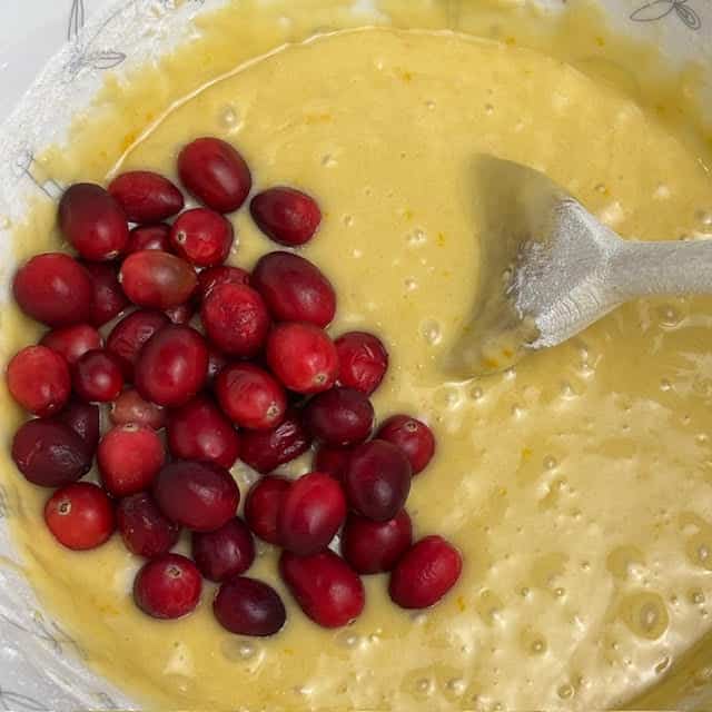 Cranberries being added to the batter for the moist cranberry orange bread.