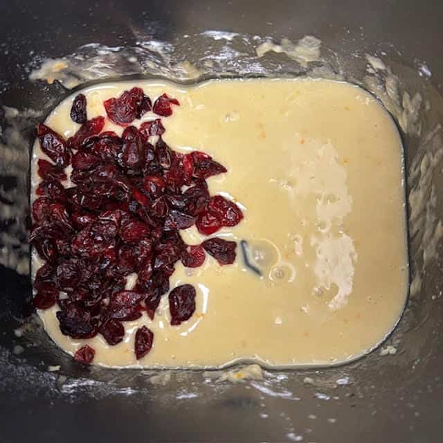 Dried cranberries being added to the batter for bread machine cranberry orange bread.