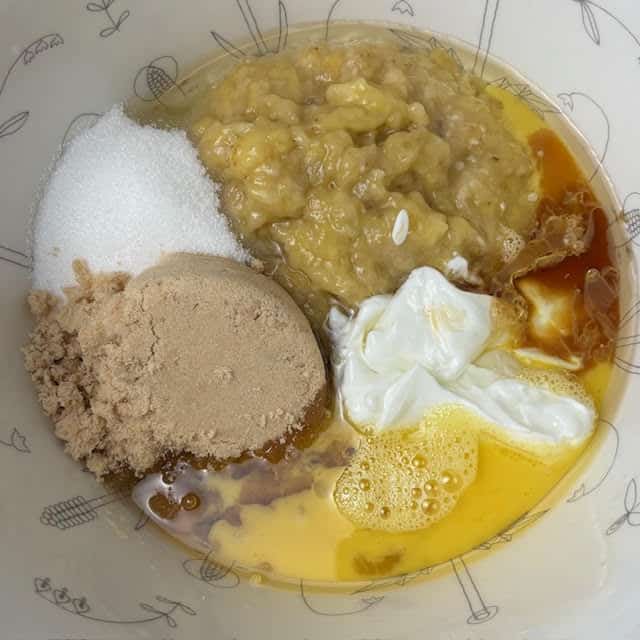 Wet ingredients and sugar for moist banana bread in mixing bowl.
