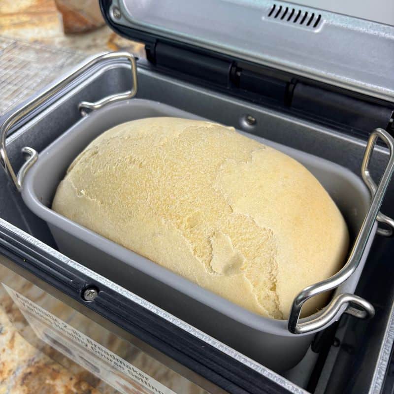 Bread machine gluten free bread in a bread pan inside a bread machine.