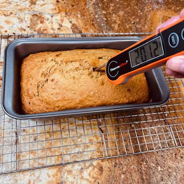 Banana bread being tested with a digital thermometer.