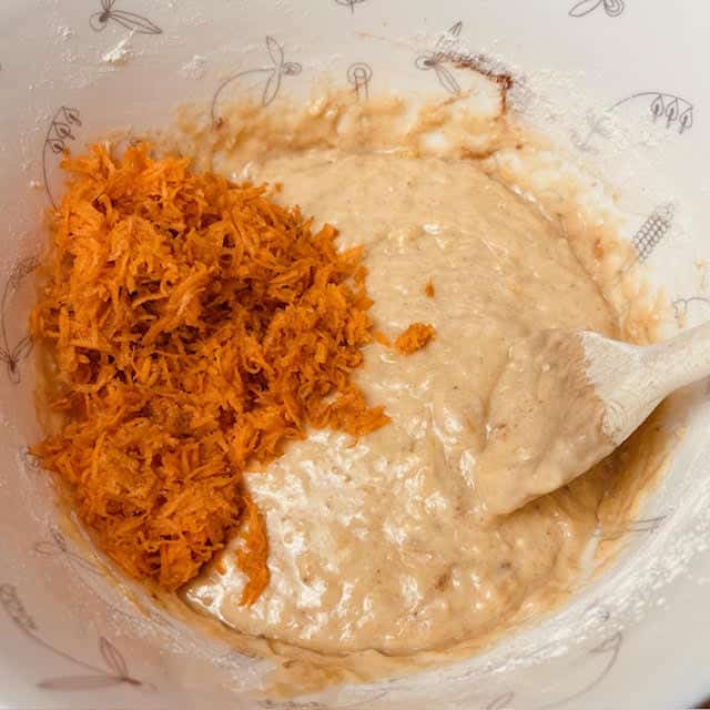 Grated carrot being added to the banana bread batter.