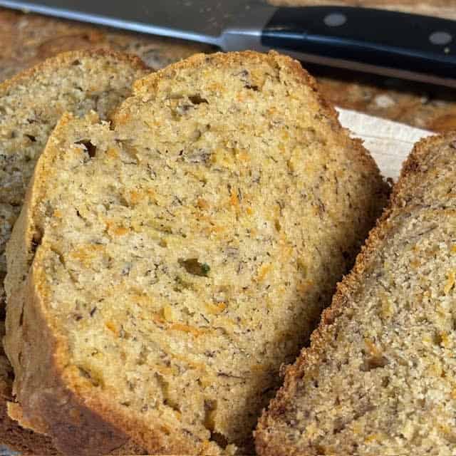 Slices of a carrot banana bread on a wooden cutting board.