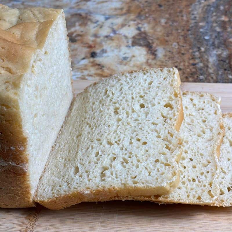 Slices of bread machine gluten free bread on a wooden cutting board.