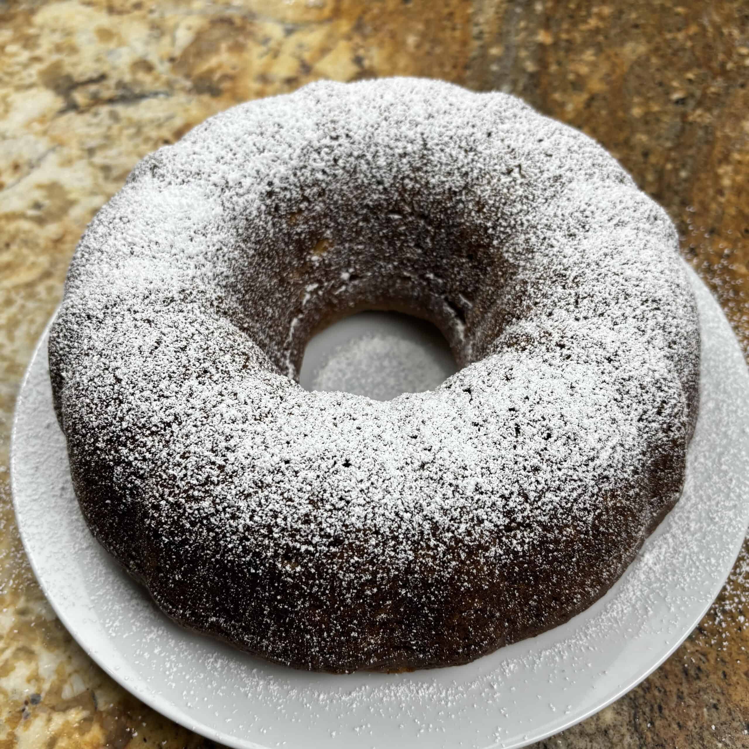 Bundt banana bread with powdered sugar topping on a white plate.
