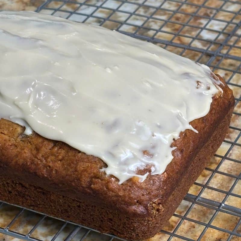 Maple banana bread with a maple glaze on a wire cooling rack.