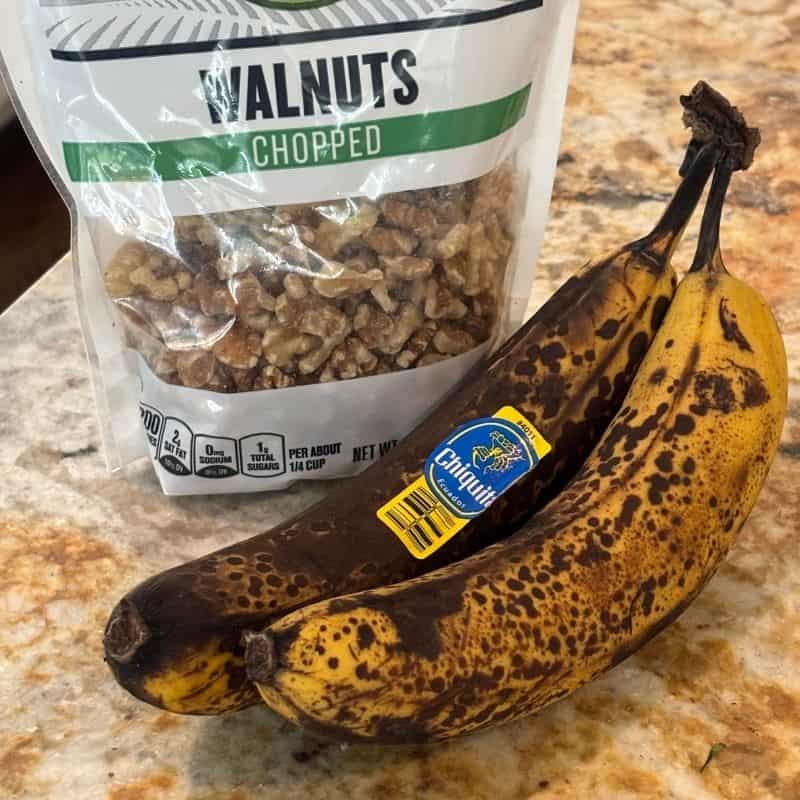 A bag of chopped walnuts and 2 bananas used to make a 2 banana nut bread.