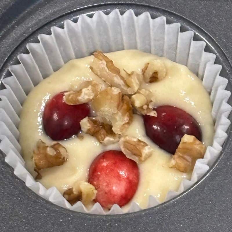 Batter for cranberry walnut muffins in a muffin tray.